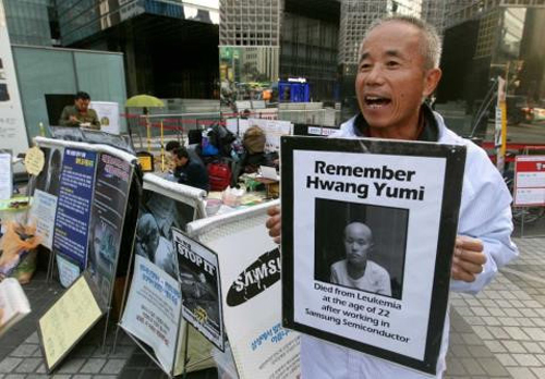 Ông Hwang Sang-gi cầm ảnh con gái qua đời vì nhiễm bệnh sau khi làm việc ở Samsung để phản đối tập đoàn ngày 23/10. Ảnh: AP