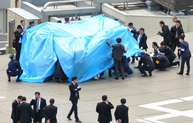 Police and security officers investigate an unidentfied drone which found on the rooftop of Prime Minister Shinzo Abe's official residence in Tokyo