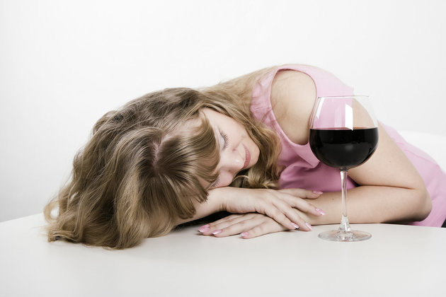 The young woman fallen asleep at a table with a wine glass