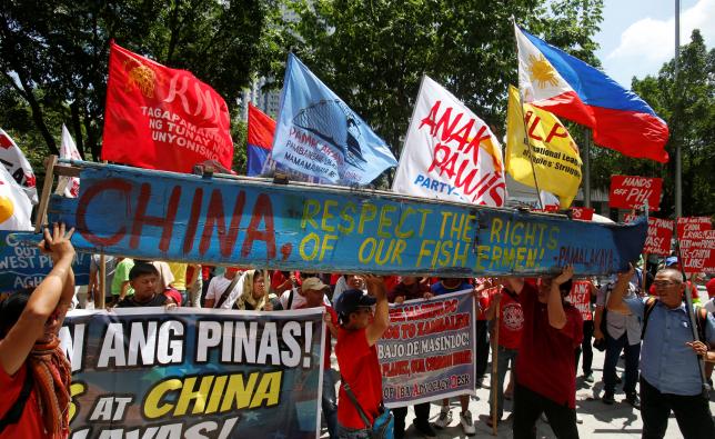 Demonstrators display a part of a fishing boat with anti-China protest signs during a rally outside the Chinese Consulate in Makati City