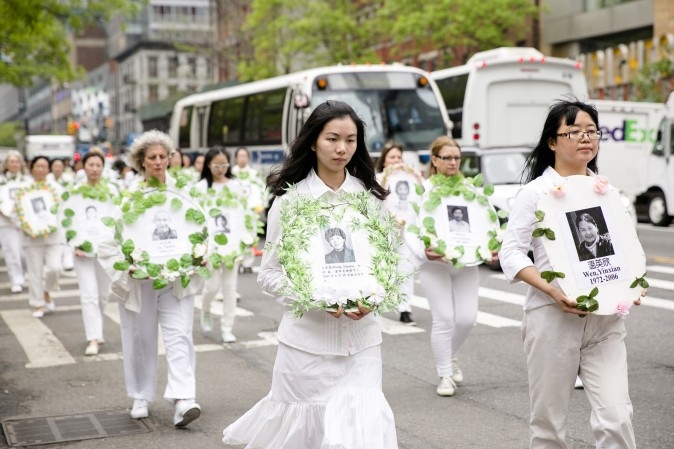 Các học viên Pháp Luân Công trong trang phục màu trắng, cầm trên tay di ảnh của các học viên đã qua đời bởi cuộc bức hại tàn khốc ở Trung Quốc. (Samira Bouaou/Epoch Times)