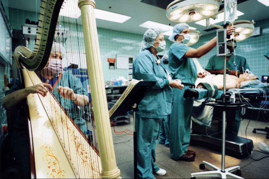 <i>Nhà trị liệu âm nhạc chơi đàn hạc trong phòng phẫu thuật để bệnh nhân giảm căng thẳng. (Ảnh qua theriverofcalm.com)</i>
