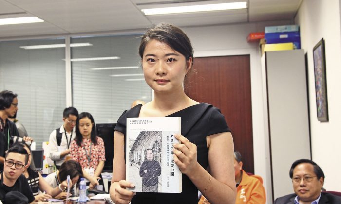 Grace Cao, con gái luật sư Cao Trí Thịnh, cầm một cuốn sách mà ông viết, trong sự kiện công bố cuốn sách tại Hồng Kông ngày 16/6/2016. (Ảnh qua The Epoch Times)