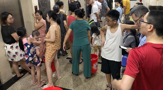 Người dân chung cư HUD3 Linh Đàm dùng xô, thùng chuyển nước từ xe téc lên căn hộ qua đường thang máy. (Ảnh qua thanhnien)