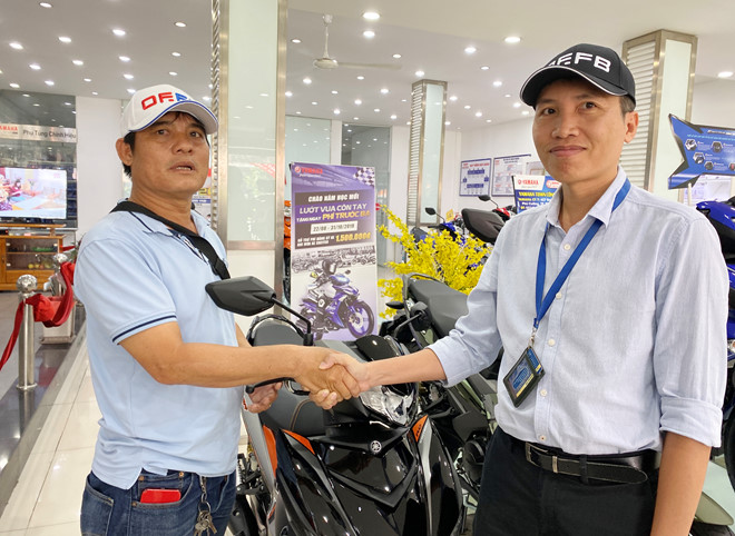 Anh Bình (bên phải) trao tặng anh Nguyễn Thanh Hải xe ngay tại cửa hàng bán xe máy. (Ảnh qua thanhnien)