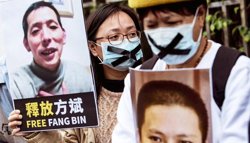 Một nhà hoạt động dân chủ (giữa) từ Liên minh HK giữ một tấm bảng của nhà báo công dân mất tích Phương Bân (Fang Bin), khi cô biểu tình bên ngoài văn phòng liên lạc Trung Quốc tại Hồng Kông vào ngày 19 tháng 2 năm 2020.