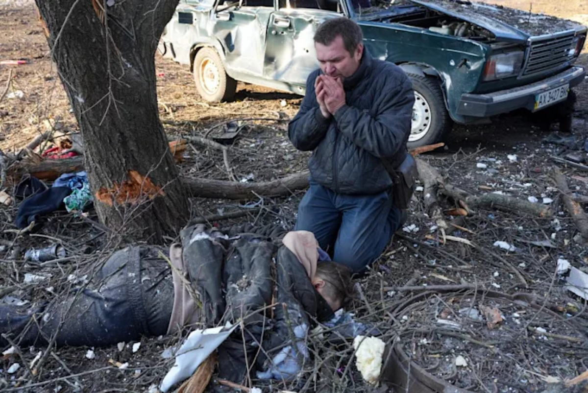 Một người đàn ông bật khóc trước bên cạnh một thi thể sau vụ không kích ở ngoại ô Kharkiv, Ukraine. (Ảnh: Anadolu Agency)